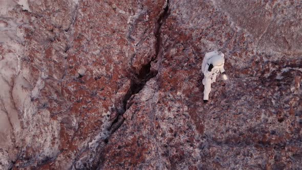 the Astronaut Carefully Descends From Cliff with a Lantern