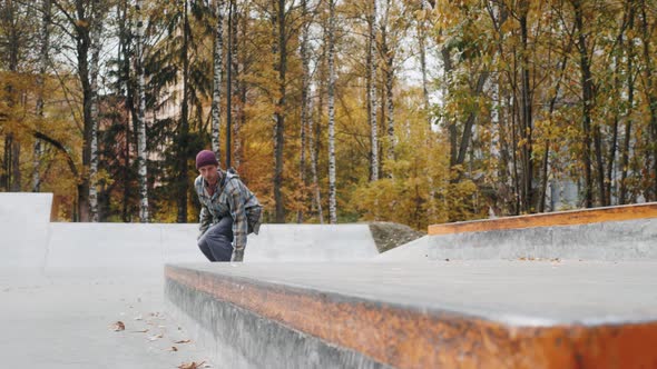 Skater Practicing in the Autumn Concrete Skate Park Making Tricks and Rides in Ramp