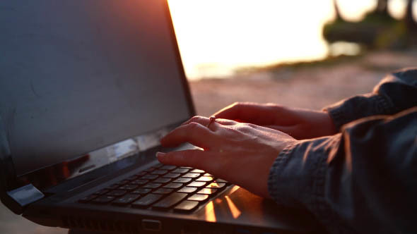 Woman Talks on a Laptop on the Beach