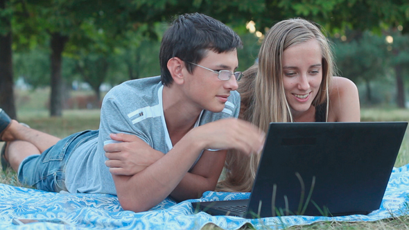 Man and Woman Talking in the Park and Using Laptop