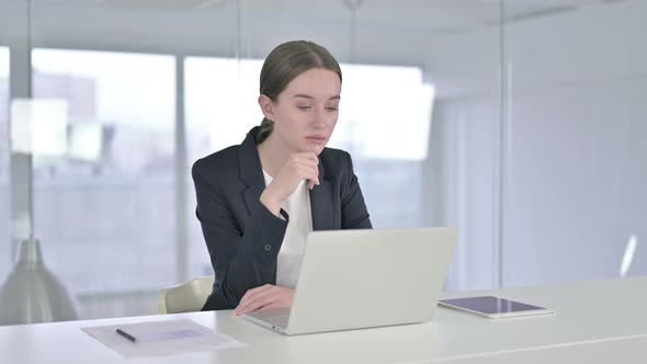 Young Businesswoman Thinking and Working on Laptop in Office
