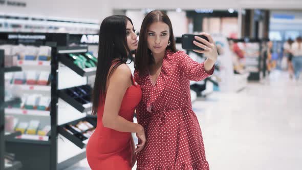 Two Pretty Young Woman Makes Selfie By Smartphone in Shopping Mall