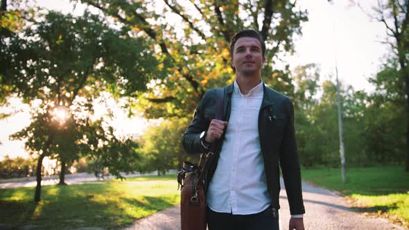 Young Handsome Man with Bag Walking in Park During Sunny Day Autumn Theme Slow Motion