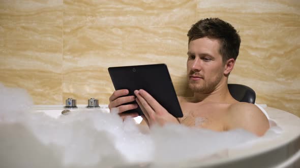 Handsome Man Relaxing After Hard Working Day Taking Bath and Watching Tv Show