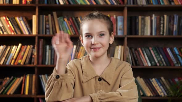 Schoolgirl in Brown Jacket Waves Hand Talks and Smiles