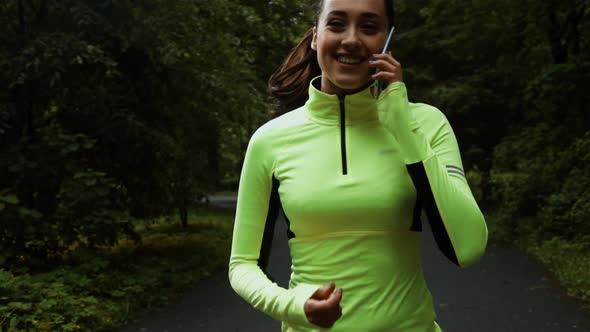 Pretty Sporty Woman Jogging and Running at Park with Smartphone