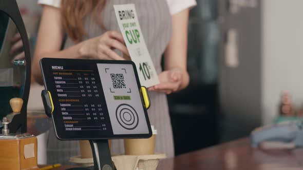 Woman barista showing gesture with menu introducing zero waste promotion and talking to customer.