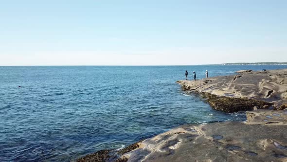 Aerial drone video of the ocean coastline and men fishing from shore at Cape Neddick and York Beach,