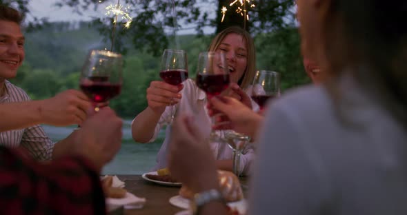 Youth Friendship Concept  Hands Toasting Red Wine Glass Beside River at Nightime