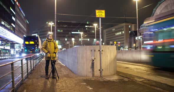 Timelapse of Man Shooting Video in Night Helsinki with Transport Traffic