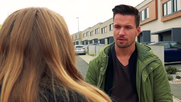 A Woman (The Back of Her Head To the Camera) Listens To an Attractive Young Man Talking on a Road