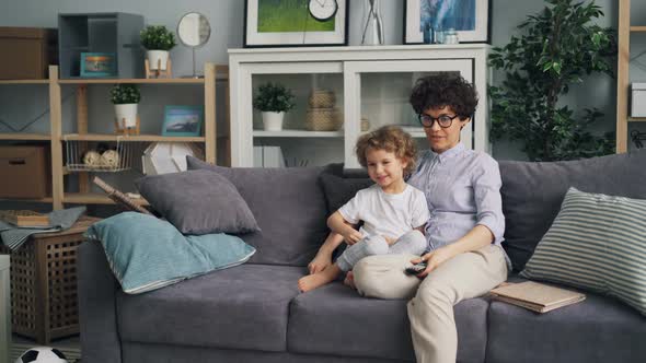 Young Woman Watching TV with Child Cute Boy Talking Enjoying Cartoons at Home