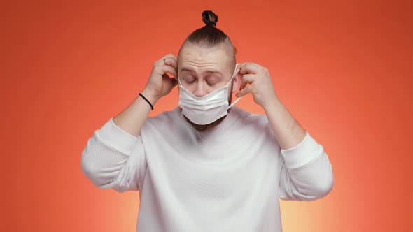 Bearded Man Is Putting on Mask and Showing Thumb Up Gesture on Red Background