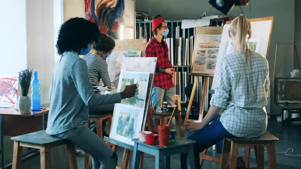 Male Artist in a Face Mask is Holding a Painting Class for Students