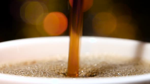 Closeup. Pouring Jet of Black Coffee in a Cup