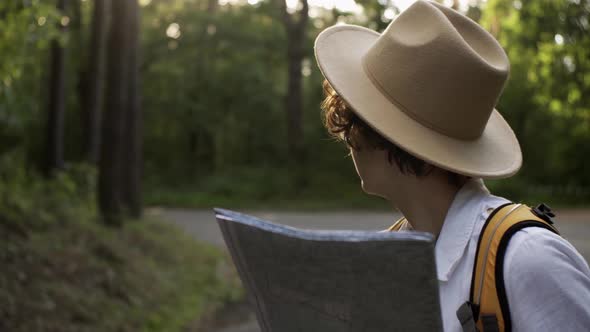 A Tourist Girl Stands On A Road In The Forest Holding A Map In Search Of A Route Girl With Backpack