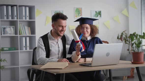 Education Online Joyful Girl in Academic Dress with Friend at Graduation Ceremony Via Video Link on