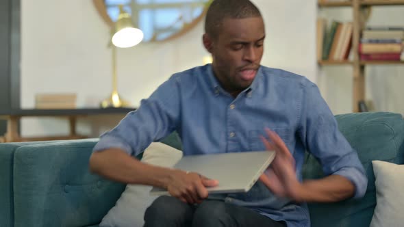 Young African Man Closing Laptop on Sofa, Going Away 