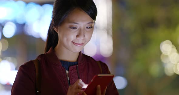 Woman use of mobile phone at night with city bokeh background