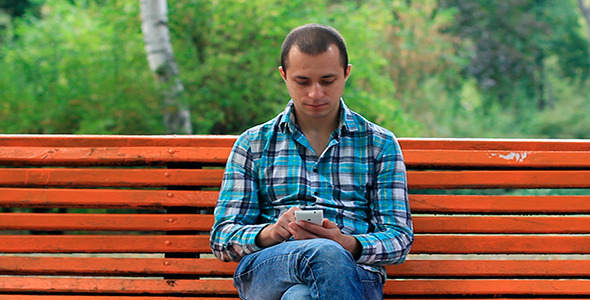 Young Man Talking On The Phone In The Park