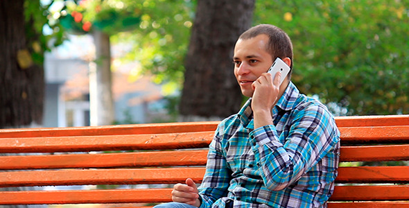 A Young Man Talking On The Phone In The Park 