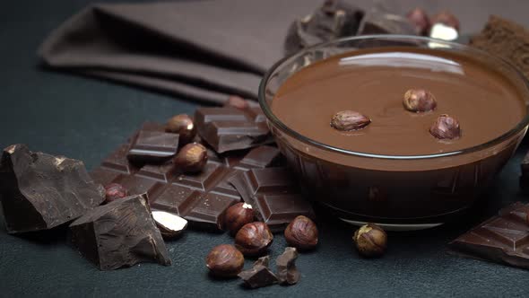 Glass Bowl of Chocolate Cream or Melted Chocolate, Pieces of Chocolate and Hazelnuts