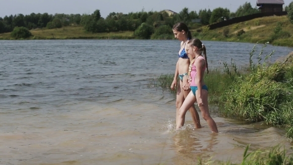 Young Girls Go Into The Water Of The Lake