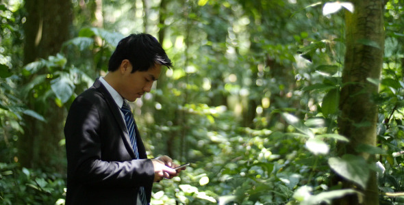 Businessman Typing Message In Forest