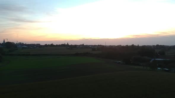 Descending aerial view of sunset over corn field