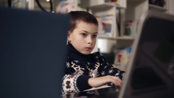 Portait Footage of a Little Boy Wth Big Blue Eyes Trying to Learn How to Use Laptop