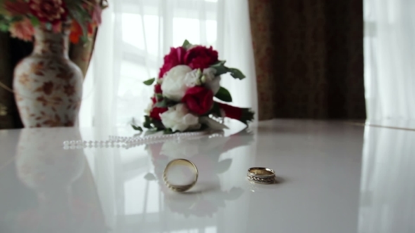 Rotating Wedding Rings Near Bouquet On The Piano