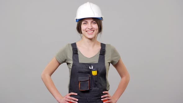 Portrait of Young Woman Employee in Helmet and Jumpsuit Laughing While Working on Factory or