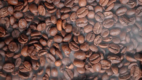 Close Up of Seeds of Coffee. Fragrant Coffee Beans Are Roasted Smoke Comes From Coffee Beans.