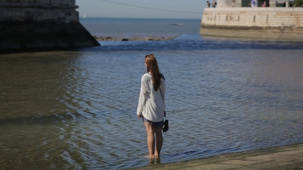 Young Woman Sightseeing, Walking Shoeless In Water