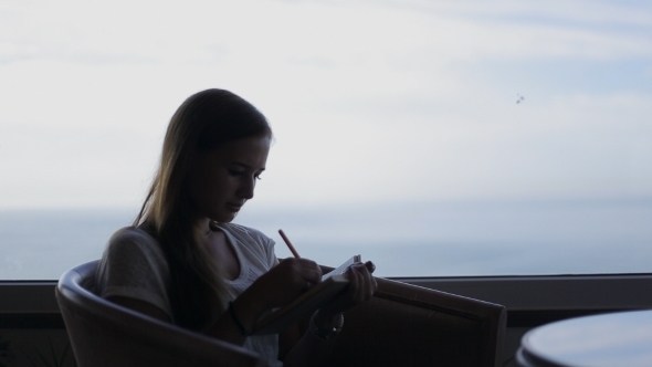 Young Beautiful Girl Sits In a Cafe