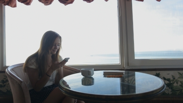 Young Beautiful Girl Sits In a Cafe