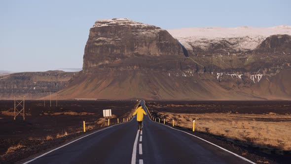 Back View of a Man Running Along an Empty Asphalt Mountain Road in Iceland