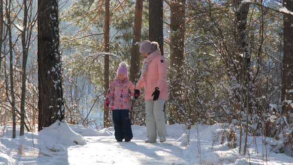 Littler Girl with Mother Walking in Winter Forest