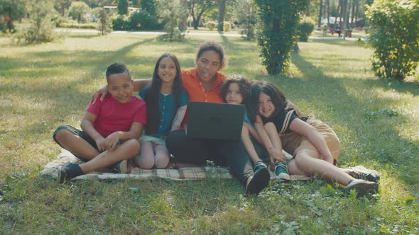 Smiling Children and Woman Looking at Camera Studying in Public Park