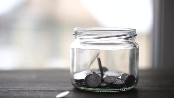 Ukrainian coins falling into the glass jar, close up. Slow motion 