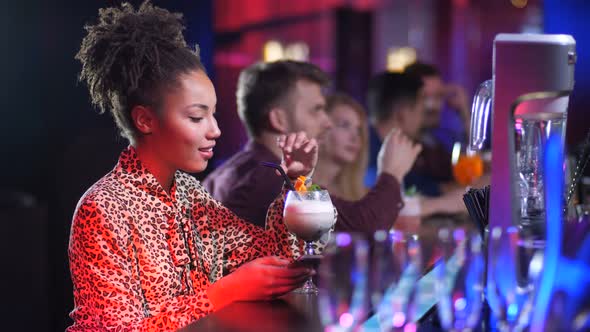 Pretty Female with Phone Drinking Cocktail at Bar