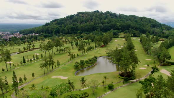 Tropical vibrant golf course near foothills of Tidar in Magelang, Indonesia, aerial view