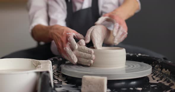 Front View of Mother and Son Hands Making Ceramic Pot on Pottery Wheel
