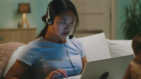 Busy Mother Browsing Netbook Near Toddler