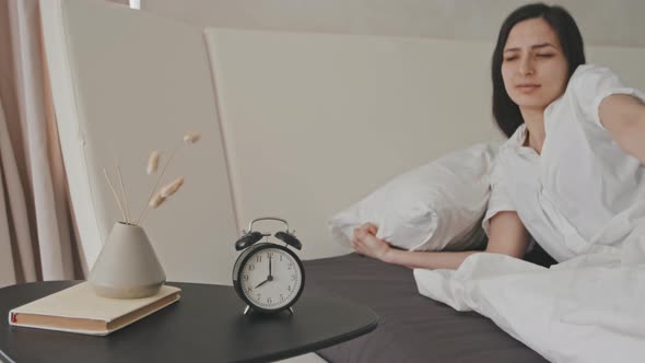 Sleepy Young Woman Turning Off Alarm Clock