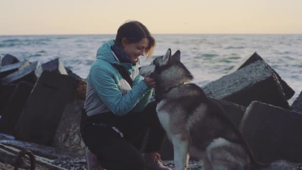 Young Beautiful Female Walking with Siberian Husky Dog on the Beach at Sunset Slow Motion