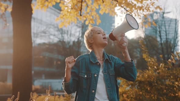 Young Blond Woman Giving an Announcement Using Loudspeaker in the Park 
