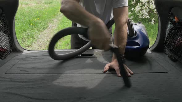 Gentleman Vacuums Automobile Trunk with Vacuum Cleaner Hose