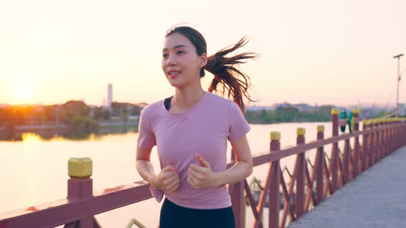 Asian young beautiful sport woman running on street in public park.