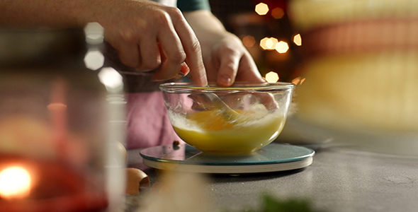 Woman Stirs Eggs with a Fork in a Glass Bowl